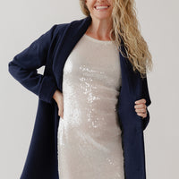 Woman wearing a navy blue wool coat over a sparkly dress