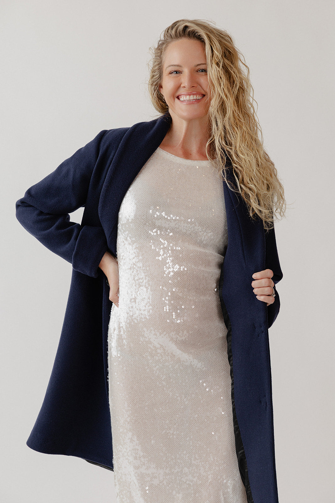 Woman wearing a navy blue wool coat over a sparkly dress