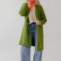 Woman wearing a knee-length green wool coatigan with hidden magnetic closure