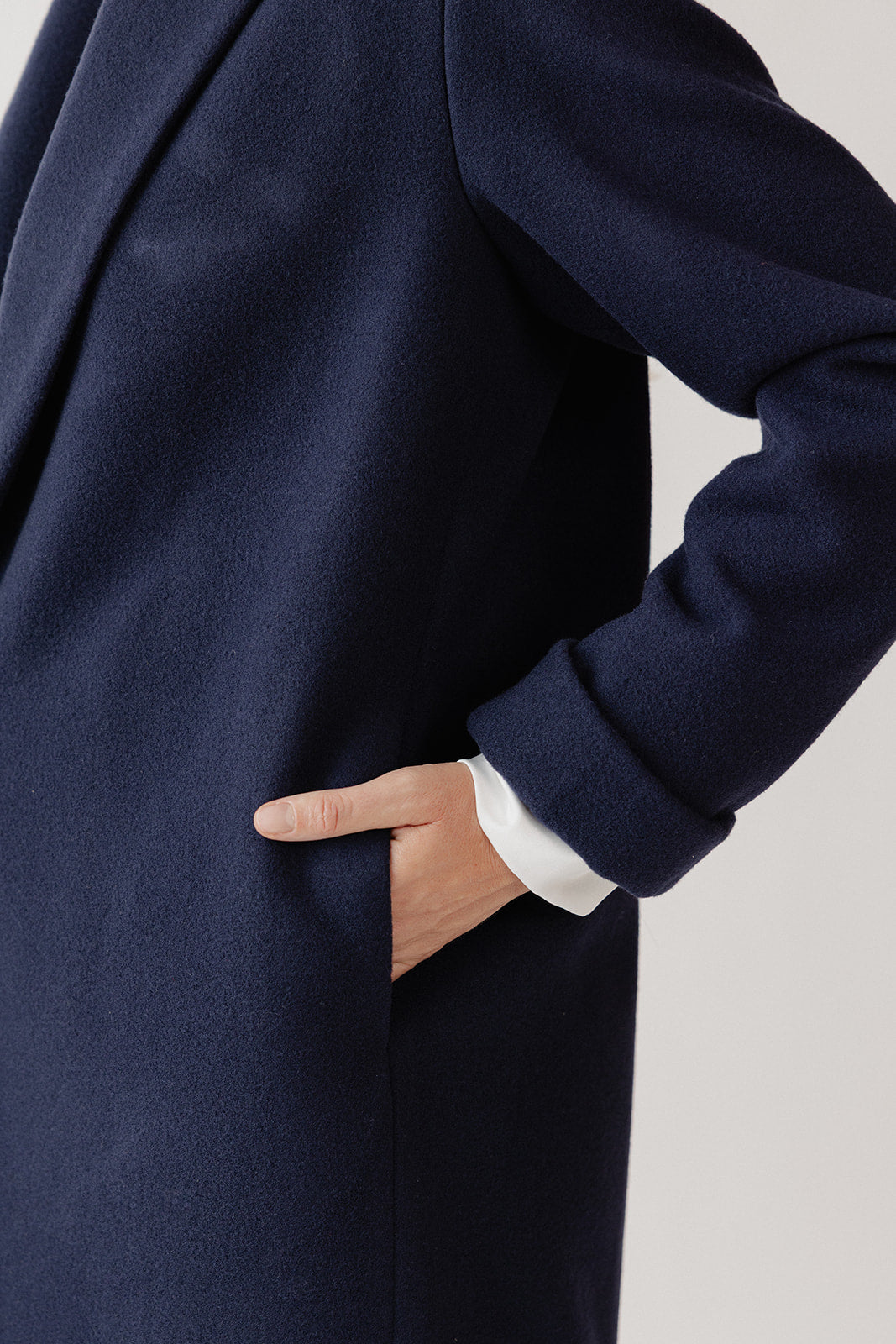 Pocket detail, side view of navy blue wool coat