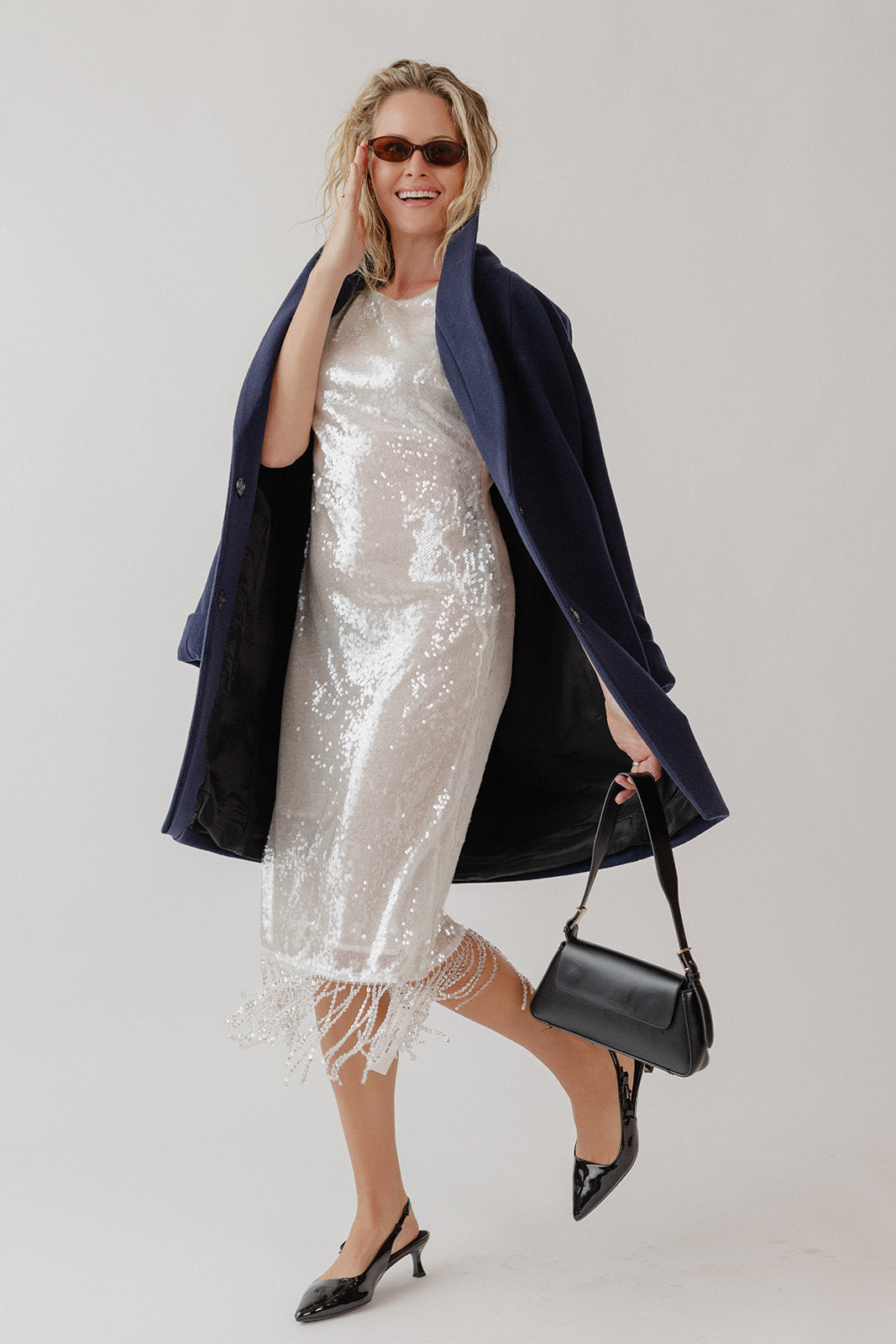 Woman wearing a sparkly dress with a navy blue wool coat.